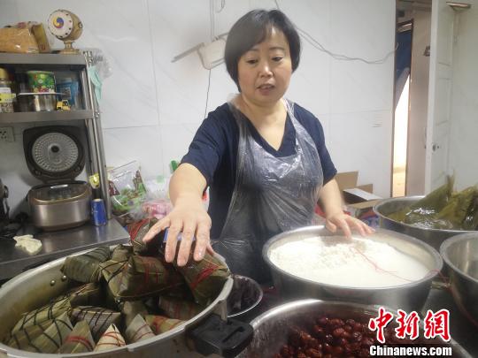 鄭春玲將兩張大粽葉窩成漏斗狀，填上糯米，放上兩粒紅棗，再加一片小粽葉，用棉線纏繞綁好，一個(gè)紅棗粽就成了，用時(shí)僅8秒。　高康迪 攝